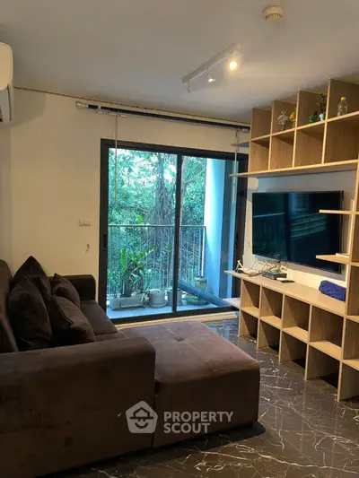 Modern living room with large TV, cozy sofa, and balcony view