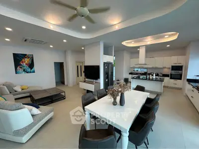 Spacious modern living room with open kitchen and elegant dining area, featuring contemporary furniture and stylish decor.