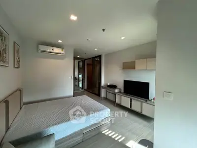 Modern bedroom with sleek design, featuring a large bed, wall-mounted TV, and air conditioning unit.