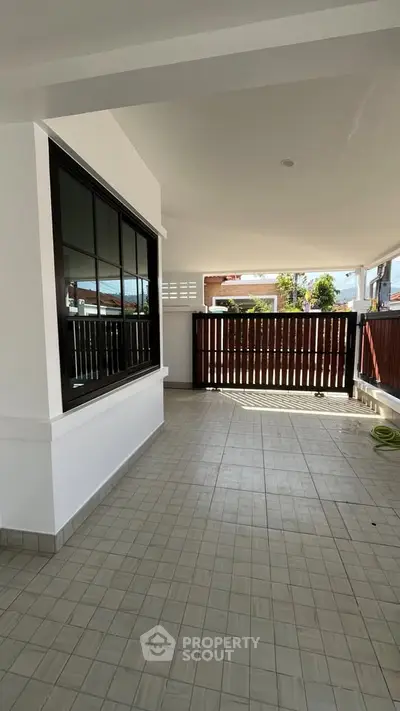 Spacious tiled patio with modern railing and large window, perfect for outdoor relaxation.