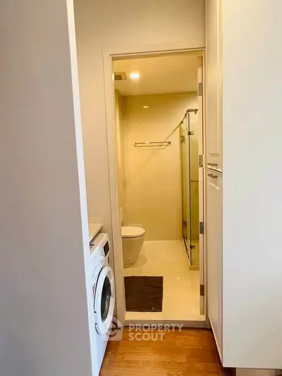 Compact bathroom with washing machine and shower in modern apartment