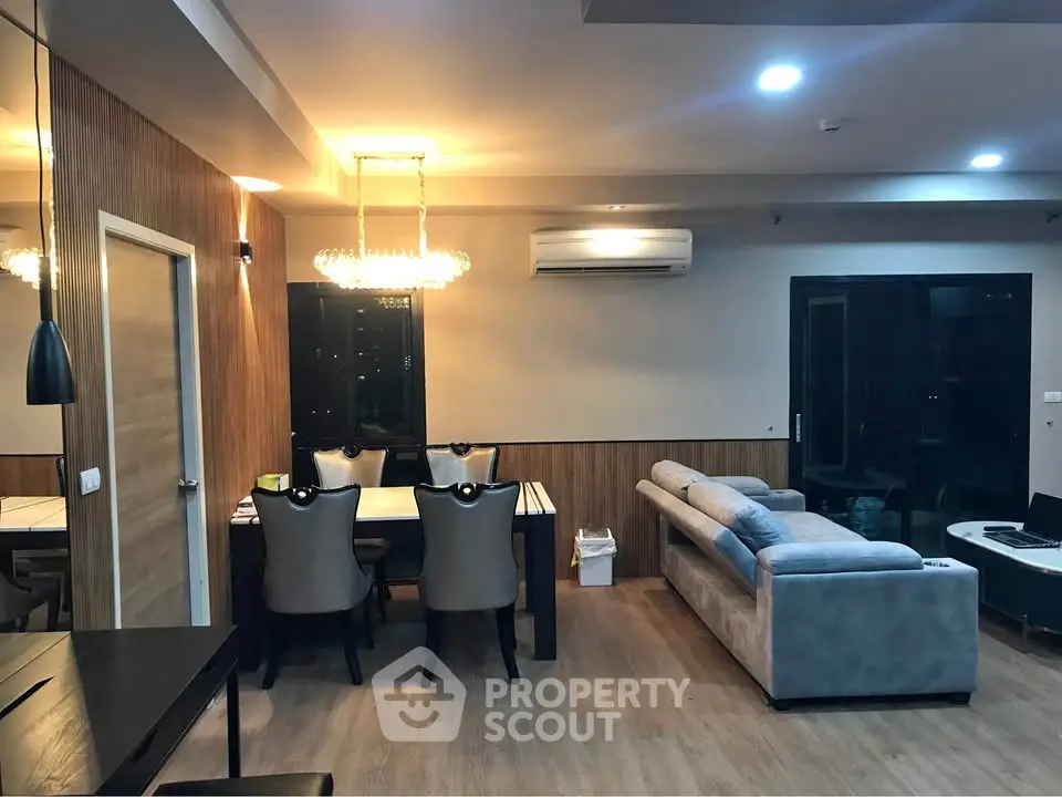 Modern living room with elegant dining area and cozy seating, featuring stylish lighting and wooden accents.