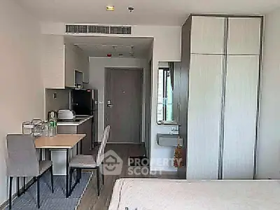 Modern studio apartment with compact kitchen and dining area, featuring sleek cabinetry and contemporary design.