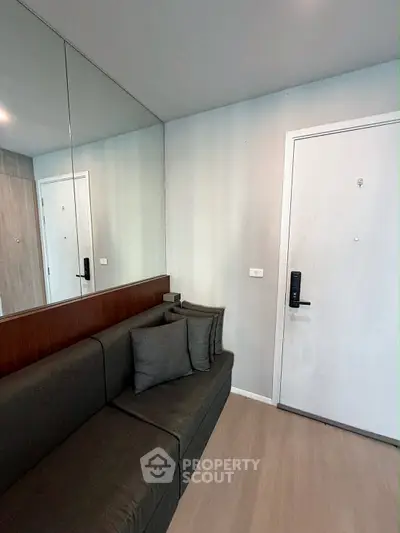 Modern apartment entrance with sleek sofa and mirrored wall for spacious feel.