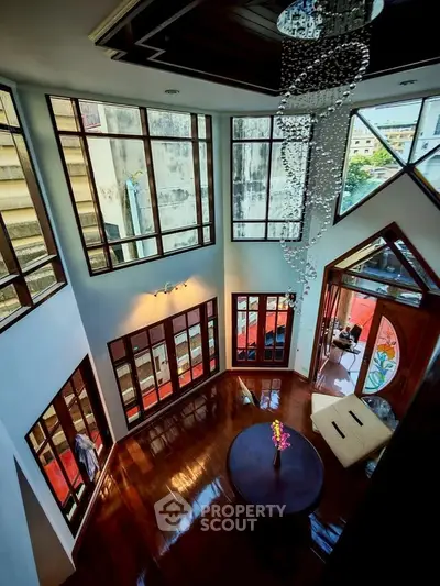 Stunning high-ceiling living room with large windows and elegant chandelier