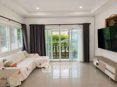 Spacious living room with large windows and modern decor, perfect for family gatherings.