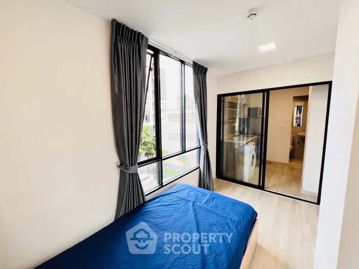 Modern bedroom with large window and washing machine in sleek apartment