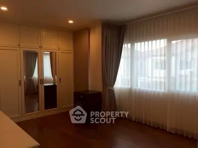 Spacious bedroom with large window and elegant curtains