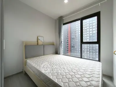 Modern bedroom with large windows and city view in a high-rise apartment.