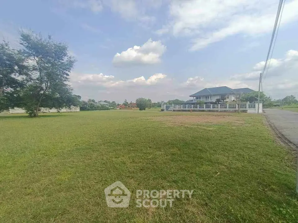 Spacious green lot with a charming house and clear blue sky, perfect for serene living.