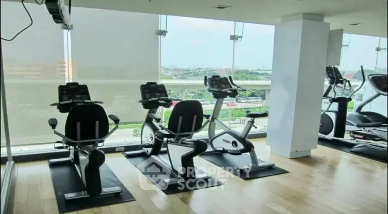 Modern gym with exercise bikes and panoramic city view.