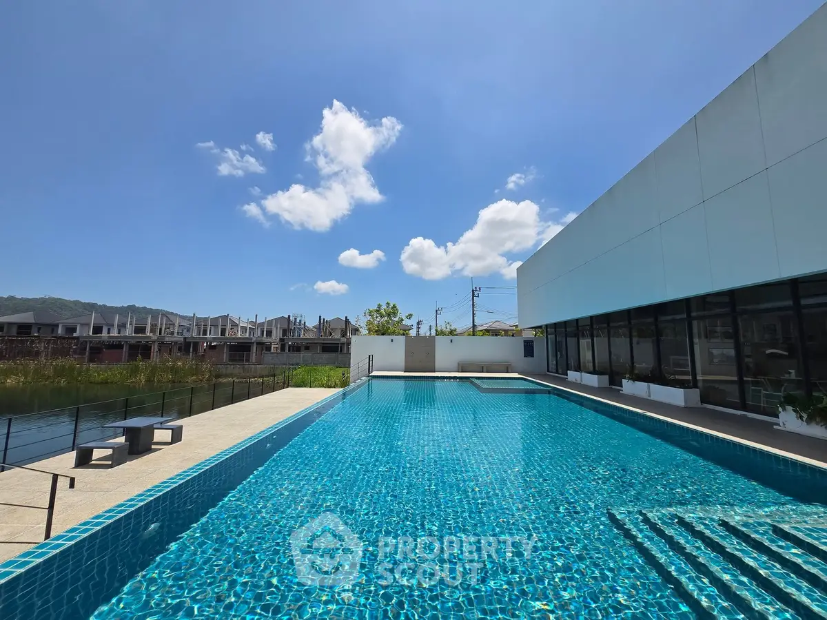 Luxurious outdoor swimming pool with clear blue water and modern building exterior under a bright sky.