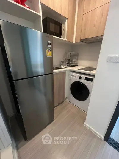 Modern compact kitchen with stainless steel fridge and washing machine