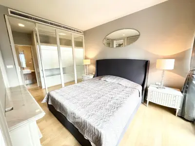 Spacious bedroom with elegant decor and ensuite bathroom in modern apartment.