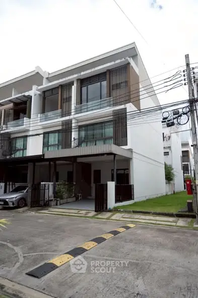 Modern multi-story townhouse with sleek design and spacious driveway in a suburban neighborhood.