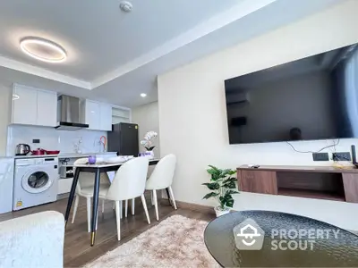 Modern open-plan living room with kitchen, featuring sleek furniture and wall-mounted TV.