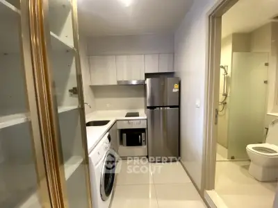 Modern compact kitchen with stainless steel fridge, washing machine, and sleek cabinetry