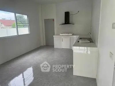 Modern kitchen with sleek white cabinetry and large window for natural light.