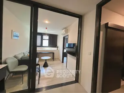 Modern living room with sleek design and natural light, featuring a cozy seating area and wall-mounted TV.