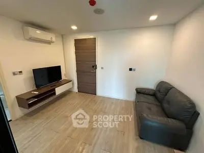 Modern living room with sleek furniture and mounted TV, featuring minimalist design and air conditioning.