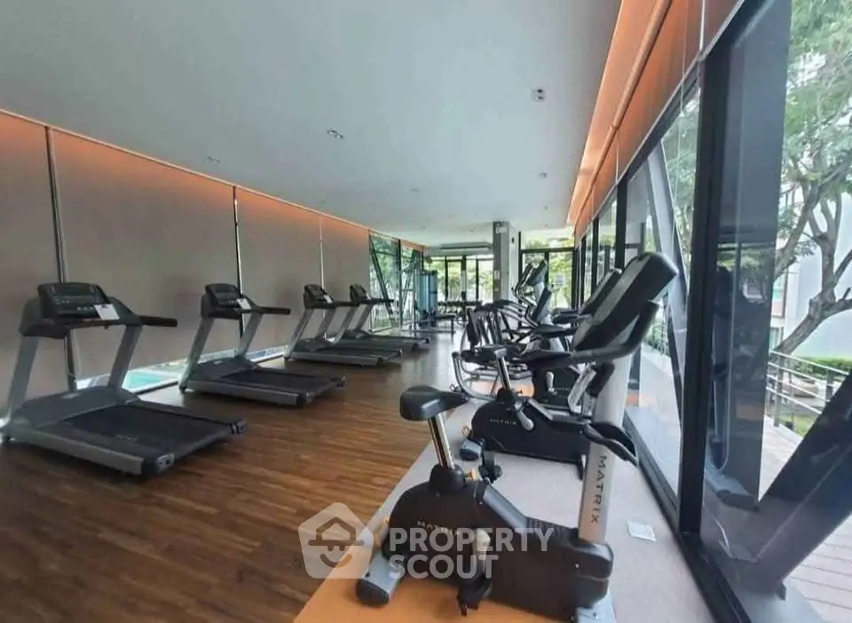 Modern gym with state-of-the-art equipment and large windows offering a scenic view.