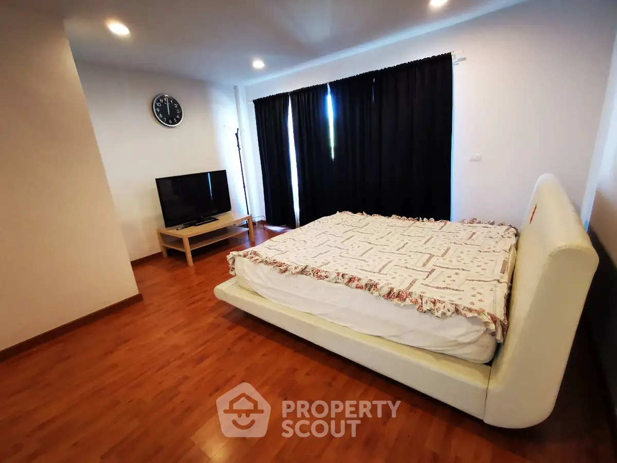Spacious bedroom with wooden flooring and modern decor