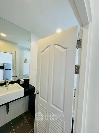 Modern bathroom with sleek sink and large mirror in contemporary apartment.
