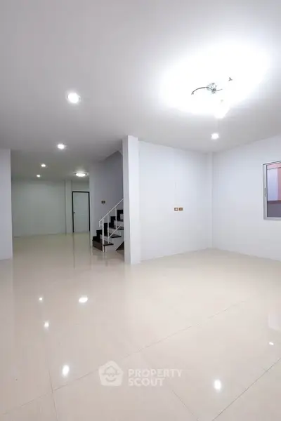 Spacious modern interior with sleek tile flooring and bright lighting, ideal for versatile living space.