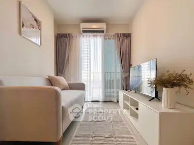 Modern living room with cozy sofa, sleek TV setup, and natural light from large window.