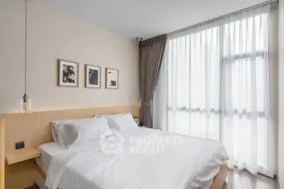 Modern bedroom with large window and stylish decor in a bright apartment.