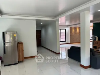 Spacious modern living room with sleek design and open layout, featuring a stainless steel fridge and elegant decor.