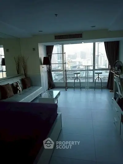 Spacious living room with city view and modern furnishings in high-rise apartment.