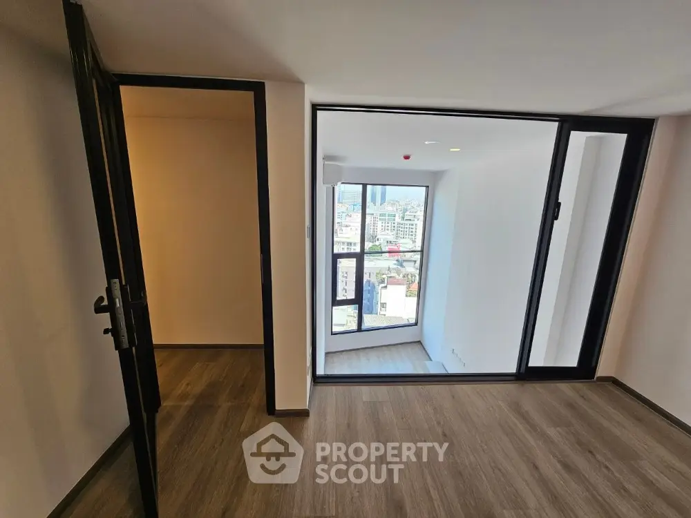 Spacious and bright corner unit with large windows offering a panoramic city view, modern flooring, and a versatile open layout.