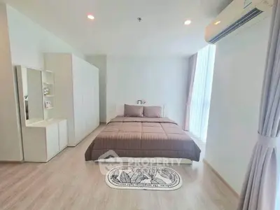 Spacious bedroom with modern decor and natural light, featuring a cozy bed and sleek wardrobe.