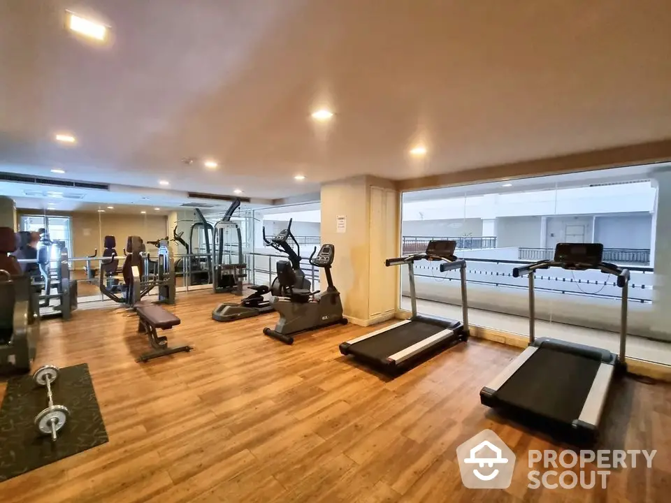 Spacious gym with modern equipment and wooden flooring in luxury apartment complex