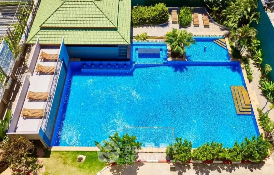 Luxurious outdoor pool area with sun loungers and lush greenery, perfect for relaxation.