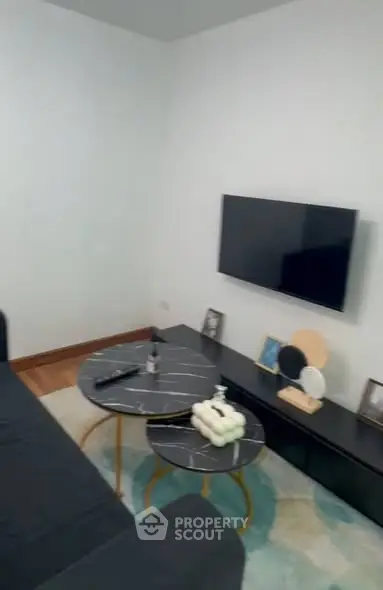 Modern living room with sleek black furniture and wall-mounted TV