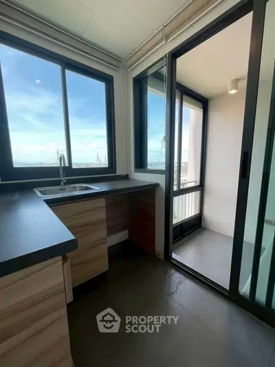 Modern kitchen with sleek countertops and balcony access offering stunning views.