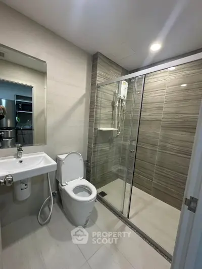 Modern bathroom with glass shower and sleek fixtures in contemporary apartment.