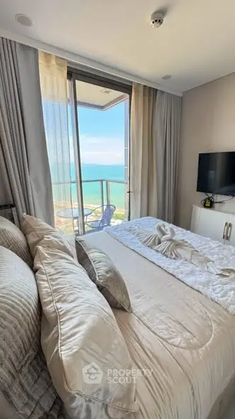 Luxurious bedroom with ocean view and balcony access, featuring elegant decor and modern amenities.