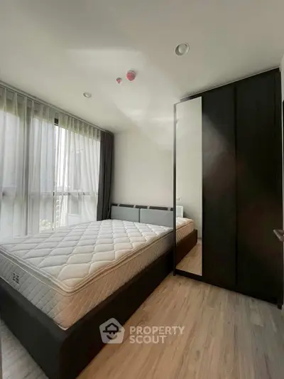 Modern bedroom with large window and sleek wardrobe in a stylish apartment.