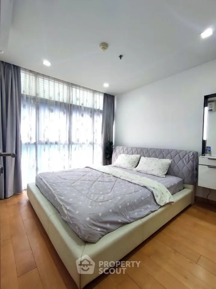 Spacious bedroom with modern decor and large window for natural light