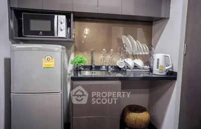 Modern compact kitchen with microwave and fridge in stylish apartment