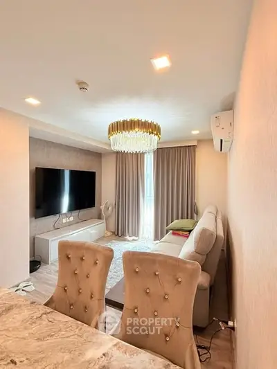 Elegant living room with modern decor and large TV, featuring plush seating and stylish lighting.