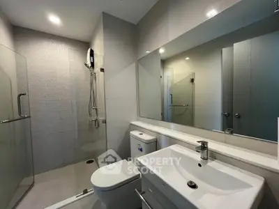Modern bathroom with sleek fixtures and spacious shower in contemporary apartment.