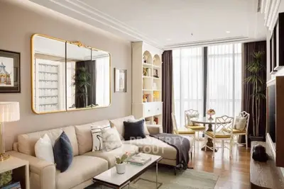 Elegant living room with large mirror, cozy sofa, and dining area by the window in a modern apartment.