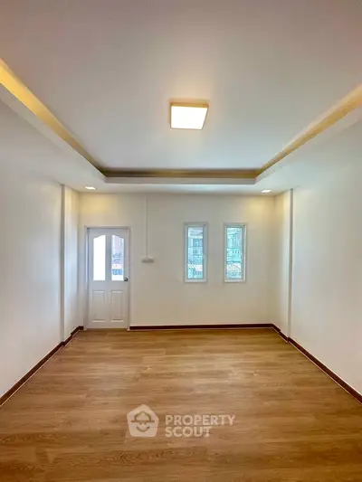 Spacious empty room with wooden flooring and modern ceiling light, ideal for customization.