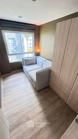 Cozy small living room with a sofa and large window offering natural light.