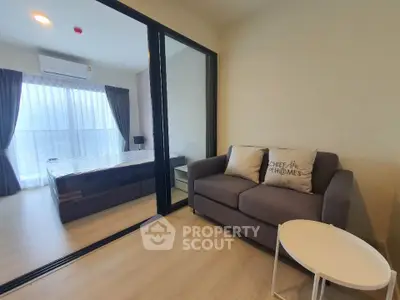 Modern apartment with cozy living room and bedroom separated by glass partition, featuring stylish decor.