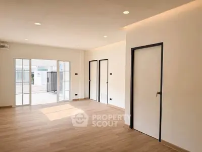 Spacious modern living room with wooden flooring and large windows for natural light.